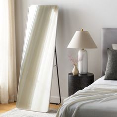 a large mirror sitting on top of a bed next to a lamp