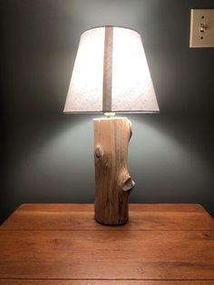 a wooden table with a lamp on top of it next to a night stand and wall light