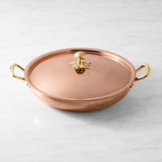 a copper pan with handles on a marble counter