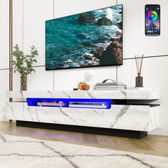 a tv is mounted on the wall above a white marble console table with blue accents