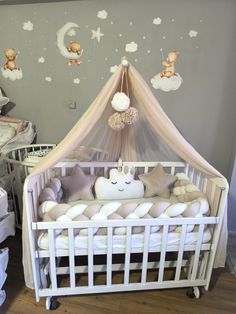 a baby crib in a nursery with teddy bears on the wall and clouds above it