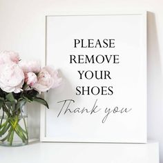 a vase filled with pink flowers sitting on top of a white table next to a sign