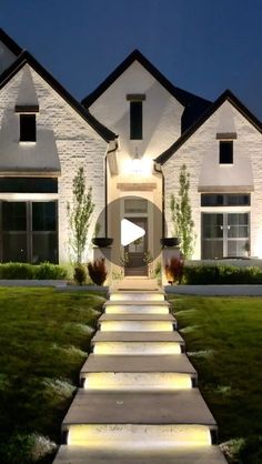 a house that is lit up at night with steps leading to the front door and lawn