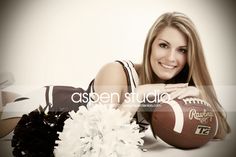 a woman laying on the ground with a football and cheerleader pom poms