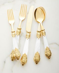 four gold and white utensils on a marble table