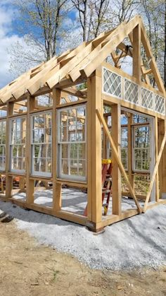 a small wooden house with windows and doors on the roof is being built in front of some trees