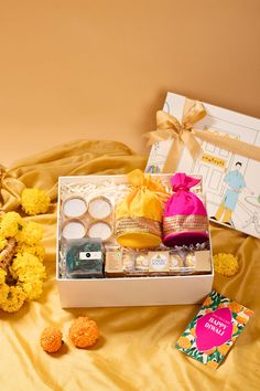 an open box containing various items on a bed with yellow sheets and flowers in the background