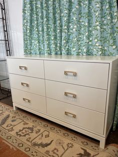 a white dresser sitting in front of a window