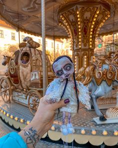 a person holding a doll in front of a merry go round