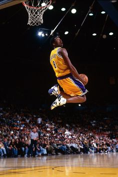 a basketball player jumping up into the air to dunk a ball in front of an audience