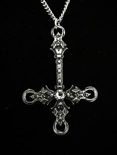 The Blasphemet is an artistic piece handcrafted in fine pewter, featuring a striking inverted cross design adorned with four demon heads and a Swarovski crystal in the color of your choice. This pendant comes with an 18-inch stainless steel chain, designed to be both hypoallergenic and durable. Made from high-quality materials, including 98% tin. The inverted cross measures 6.5 cm and each necklace is accompanied by a certificate of authenticity, confirming that it has been entirely handcrafted Medieval Silver Cross Pendant Jewelry, Medieval Cross Metal Jewelry, Medieval Silver Cross Jewelry, Gothic Stainless Steel Cross Pendant Jewelry, Gothic Silver Pendant Cross Necklace, Gunmetal Cross Metal Jewelry, Gothic Cross Pendant With Oxidized Finish, Gothic Oxidized Cross Pendant Jewelry, Gothic Silver Metal Cross Necklace