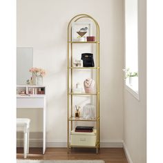 a gold shelving unit in a room with white walls and wooden floors, along with a rug on the floor