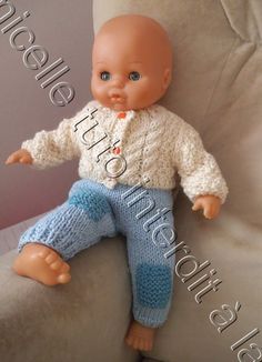 a baby doll sitting on top of a white chair with blue pants and a sweater