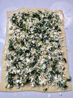 an uncooked pizza with cheese and spinach