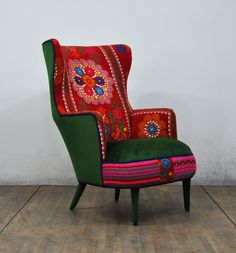 a colorful chair sitting on top of a hard wood floor next to a white wall