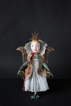 the doll is dressed in an old fashion dress and headdress, with wings outstretched