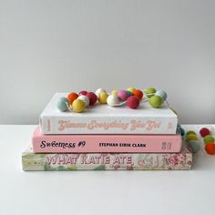 three books stacked on top of each other with pom - poms attached to them