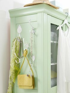 a green cabinet with a purse hanging on it