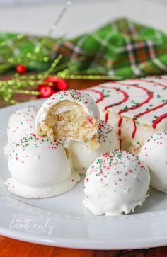 a white plate topped with cake covered in frosting and sprinkles next to a christmas tree