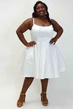 a woman in a white dress posing for the camera with her hands on her hips