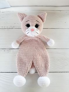 a crocheted cat stuffed animal laying on top of a white wooden floor