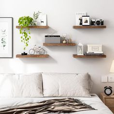 a bedroom with white walls and wooden shelves above the bed