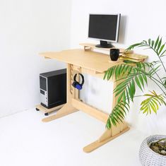 a computer desk with a monitor, keyboard and mouse next to a potted plant