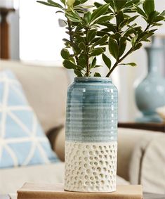 a blue and white vase sitting on top of a wooden table next to a couch