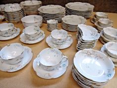 a table topped with lots of white plates and cups on top of a wooden table