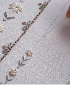 someone is stitching flowers on a piece of fabric