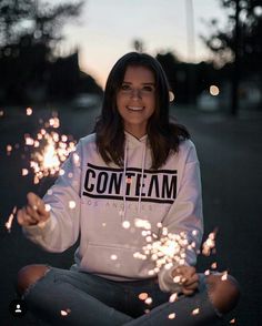 a woman sitting on the ground holding sparklers