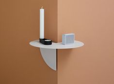 a white shelf with a candle and speaker on it