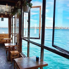 an empty restaurant with tables and benches overlooking the water