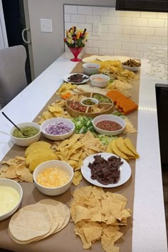 a table filled with chips, salsa and tortilla shells next to bowls of condiments