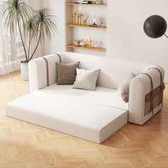 a white couch sitting on top of a wooden floor next to a potted plant