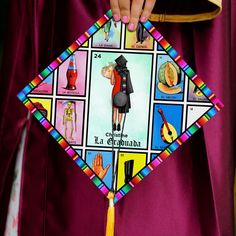 a person holding a colorful kite with pictures on it's sides and the words in different languages