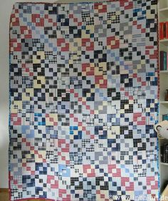 a large quilt hanging on the wall next to a bookshelf filled with books