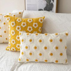 three yellow and white pillows sitting on top of a bed next to a framed photograph