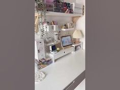 a white desk topped with lots of shelves filled with books and office supplies on top of it