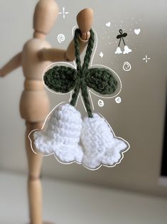 a wooden doll holding onto a string with a green butterfly on it's back