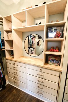 an organized closet with white drawers and open shelving units, including a round mirror