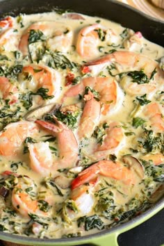 a skillet filled with shrimp, spinach and cheese