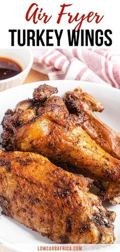 grilled chicken wings on a white plate with ketchup and sauce in the background