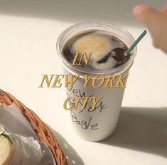 a cup of coffee next to a basket with a sandwich on it and the words in new york city