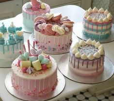 four cakes decorated in pastel colors with icing and sprinkles on them