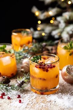 three glasses filled with drinks sitting on top of a table next to christmas decorations and baubles