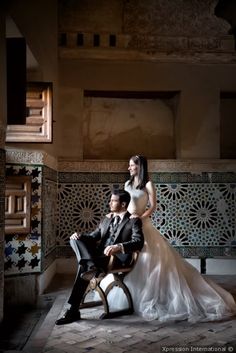 a bride and groom sitting on a chair in the middle of a room with tile walls