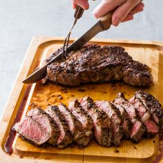 a person cutting meat with a knife on a cutting board