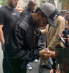 the man is signing autographs for his friends on the street while others look on