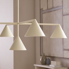 three white lamps hanging from a ceiling in a room with a mirror and table behind them